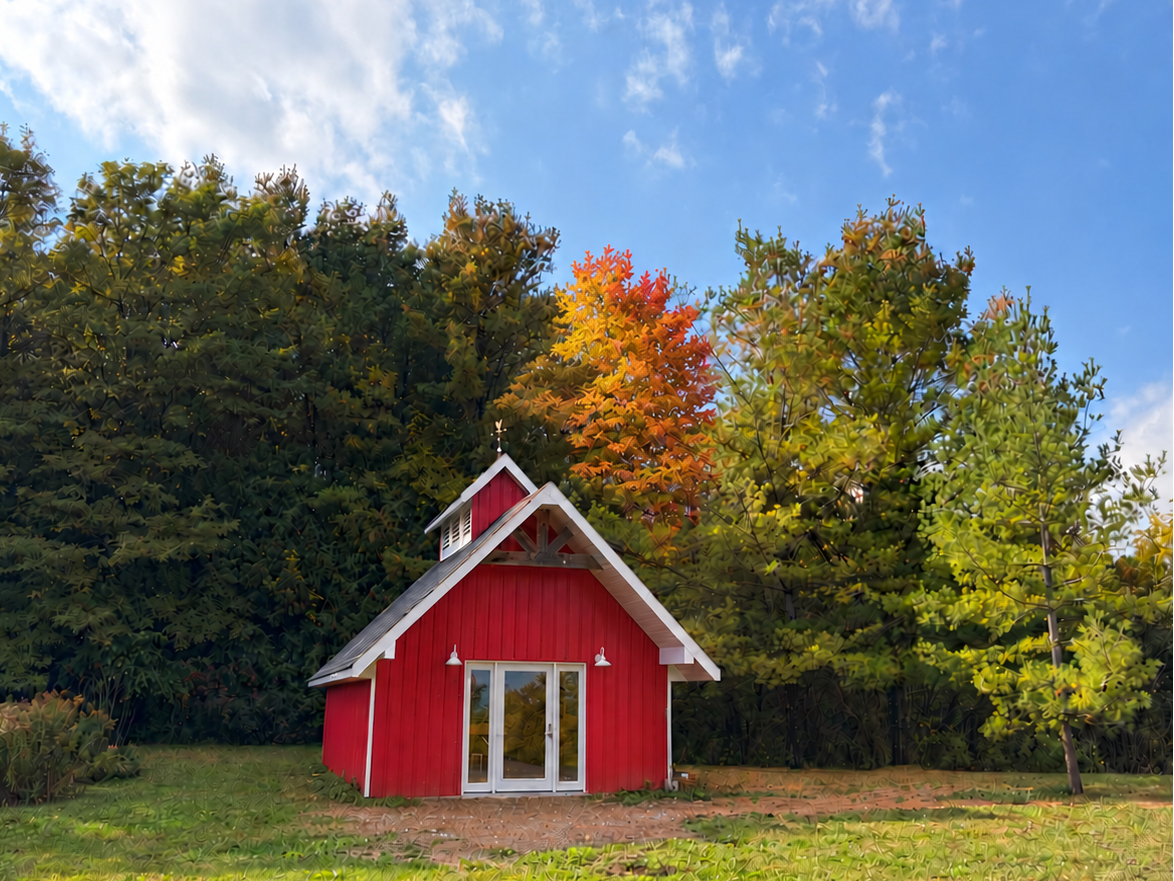 Red barn at Woodland Skin Renewal surrounded by fall trees