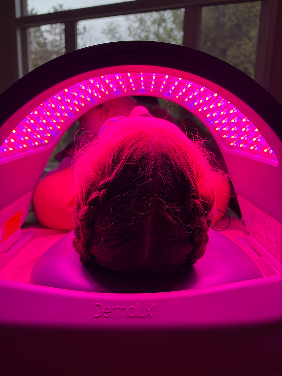 A person lying face down under a DermaLux Flex MD, with blue light, red light and near-infrared light (NIR) at Woodland Skin Renewal.